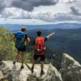 Deux randonneurs contemplent un paysage de montagnes et de forêts. Une balade Vosges facile pour admirer la vue.