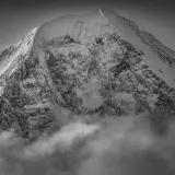 Sommet enneigé émergeant des nuages, une vision spectaculaire capturée par Guido Magnone.