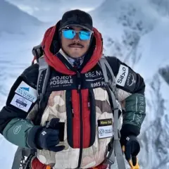 Nims Dai, alpiniste audacieux, porte sa veste "Project Possible" sur les sommets enneigés.