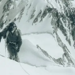 Un alpiniste progresse sur une pente enneigée, crampons aux pieds. Une scène digne d'un podcast alpinisme.