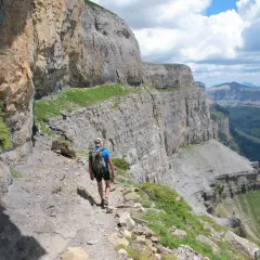 Randonneur sur le sentier escarpé de la Faja de las Flores, dominant un paysage de falaises et de vallées verdoyantes.