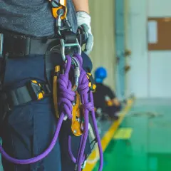 Un travailleur porte un harnais de sécurité avec une cordelette violette. Il est prêt pour une intervention en hauteur.