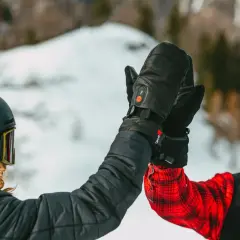 Deux skieurs se donnent une tape dans la main, portant des casques et des lunettes de ski. L'un d'eux a des gants noirs chauffants, une marque de ski de qualité.