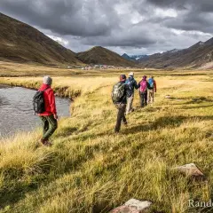 Un groupe de randonneurs s'engage dans un trek de 5 jours en France, traversant une vallée verdoyante avec une rivière sinueuse.