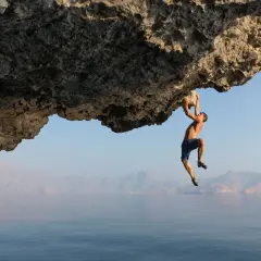Un homme suspendu à une falaise au-dessus de la mer, une véritable citation escalade pour les audacieux.