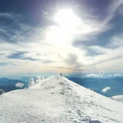 Un alpiniste solitaire au sommet du Mont Blanc, sous un ciel spectaculaire.