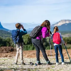 Une famille profite d'une randonnée à Font d'Urle. Le garçon utilise des jumelles, tandis que la mère et la fille consultent une carte.