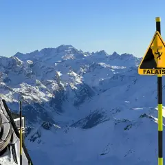 Panneau "Falaises" sur fond de montagnes enneigées, avec une remontée mécanique. Attention aux neiges mouvantes et aux dangers du relief.