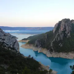 Vue spectaculaire des **pasarelas de Montfalcó** serpentant entre des falaises rocheuses et un lac aux eaux turquoise.