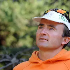 Portrait d'Ueli Steck, le célèbre alpiniste, avant son tragique accident. Il porte une casquette et un sweat orange.