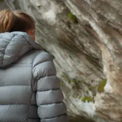 Manon, une grimpeuse, observe son partenaire escalader une paroi rocheuse.