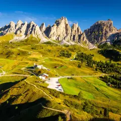 Paysage de montagne spectaculaire, avec des pics rocheux imposants et des prairies verdoyantes traversées par des sentiers. L'Alta Via 2 des Dolomites offre une vue imprenable.
