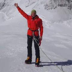 Denis Urubko, alpiniste chevronné, salue depuis un sommet enneigé, prêt pour l'ascension.