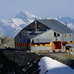 Refuge moderne sur fond de montagnes enneigées, un point de départ idéal pour le tour du Grand Combin. Panneaux solaires sur le toit.