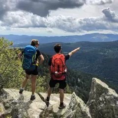 Deux randonneurs contemplent un paysage de montagnes et de forêts. Une balade Vosges facile pour admirer la vue.
