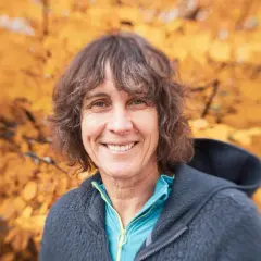 Catherine Destivelle, souriante, en tenue de sport, avec un fond d'automne. Elle est une alpiniste reconnue, un vrai compagnon de la nature.