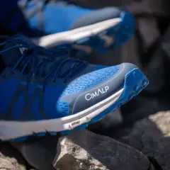Chaussures de trail bleues CIMALP sur des rochers. Le bon **taille chaussure trail** est essentiel pour l'aventure.