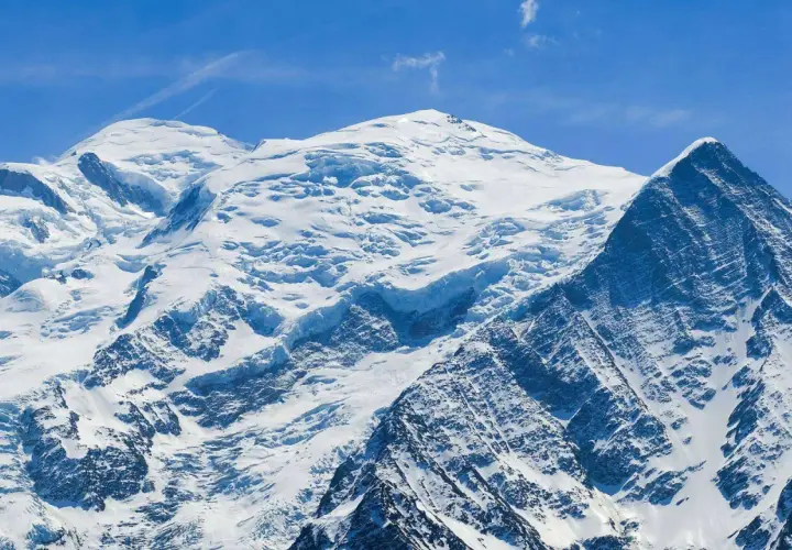 Majestueux Mont Blanc, son versant italien enneigé sous un ciel bleu éclatant. Un paysage alpin à couper le souffle.