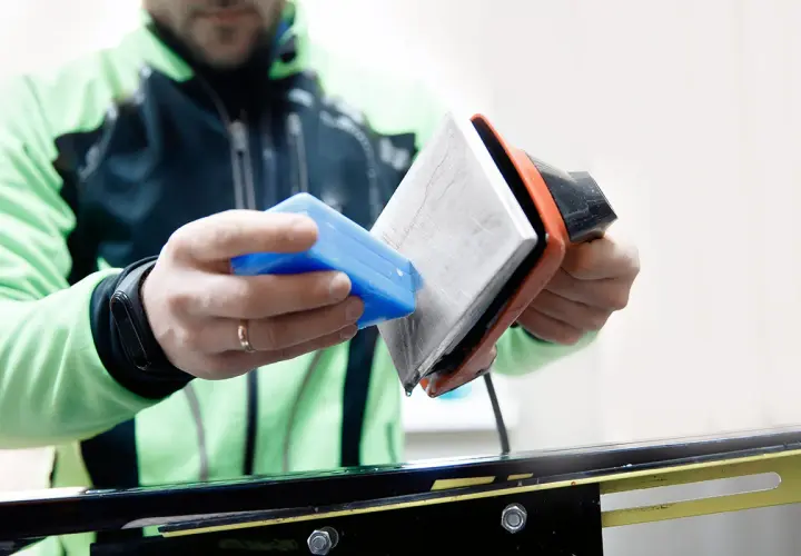 Un skieur prépare ses skis neufs. Il applique de la cire avec un fer chaud, une étape essentielle pour une glisse optimale.