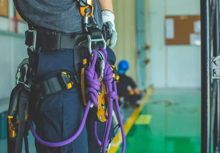 Un travailleur porte un harnais de sécurité avec une cordelette violette. Il est prêt pour une intervention en hauteur.