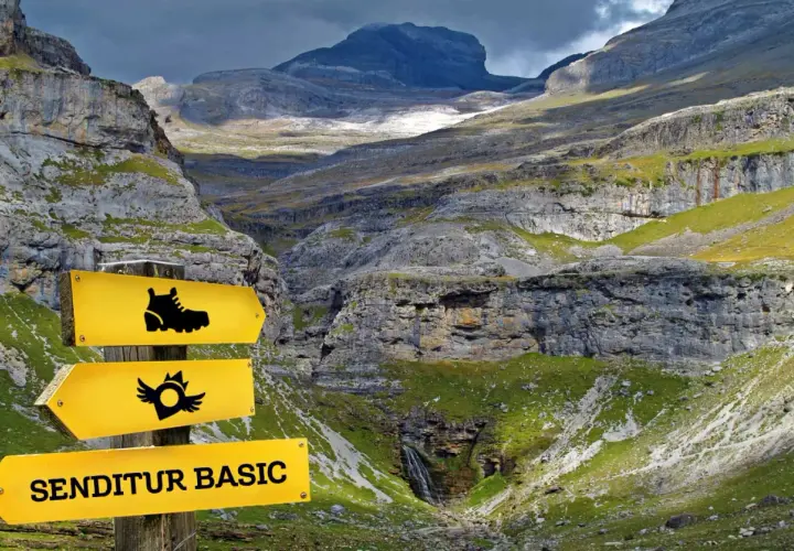 Panneau jaune indiquant "SENDITUR BASIC" dans une vallée montagneuse spectaculaire.