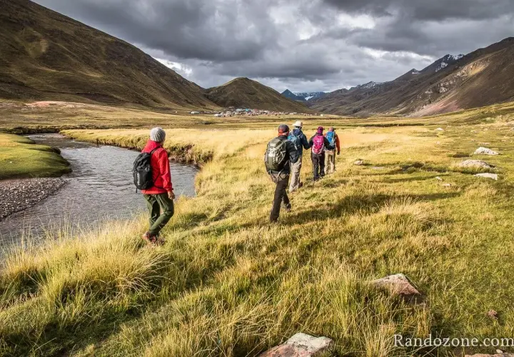 Un groupe de randonneurs s'engage dans un trek de 5 jours en France, traversant une vallée verdoyante avec une rivière sinueuse.