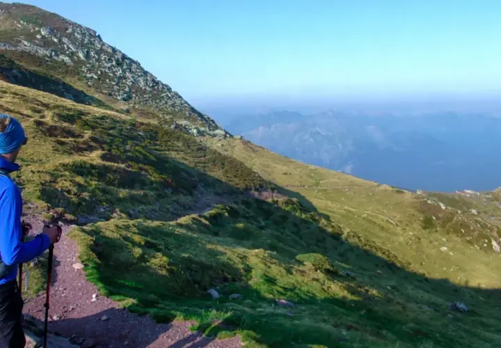 Un randonneur en bleu, prêt pour son premier trek, admire le paysage montagneux.