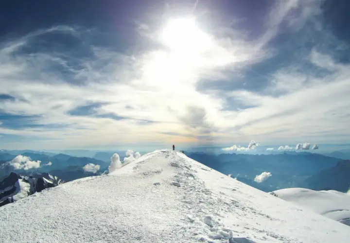 Un alpiniste solitaire au sommet du Mont Blanc, sous un ciel spectaculaire.