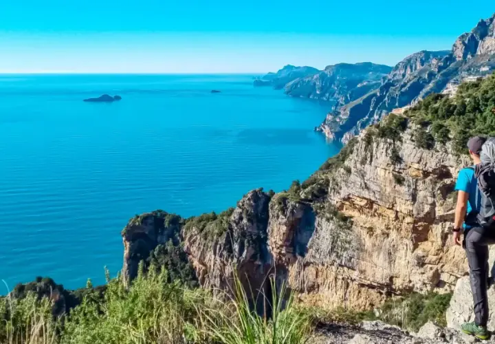 Randonnée sur la côte amalfitaine. Un randonneur admire la vue spectaculaire sur la mer bleue et les falaises escarpées.