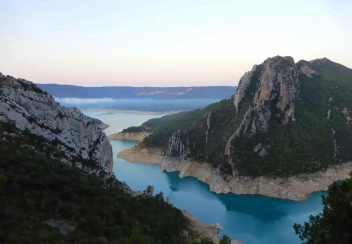 Vue spectaculaire des **pasarelas de Montfalcó** serpentant entre des falaises rocheuses et un lac aux eaux turquoise.