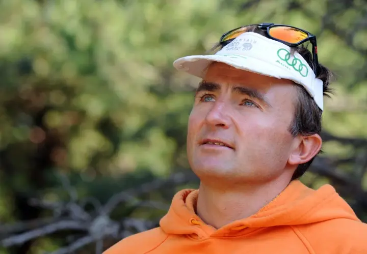 Portrait d'Ueli Steck, le célèbre alpiniste, avant son tragique accident. Il porte une casquette et un sweat orange.