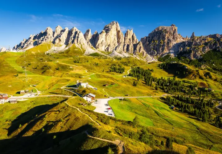 Paysage de montagne spectaculaire, avec des pics rocheux imposants et des prairies verdoyantes traversées par des sentiers. L'Alta Via 2 des Dolomites offre une vue imprenable.