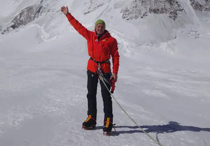 Denis Urubko, alpiniste chevronné, salue depuis un sommet enneigé, prêt pour l'ascension.