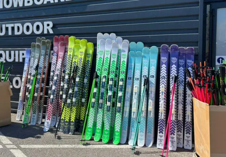 Une rangée de skis de différentes couleurs, certains avec des motifs chevron, prêts pour le freeride. La **taille ski freeride** varie pour s'adapter à tous les riders.