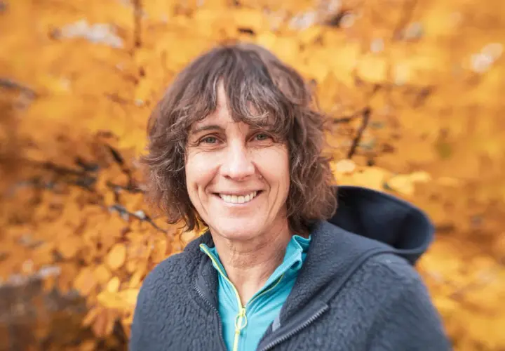 Catherine Destivelle, souriante, en tenue de sport, avec un fond d'automne. Elle est une alpiniste reconnue, un vrai compagnon de la nature.