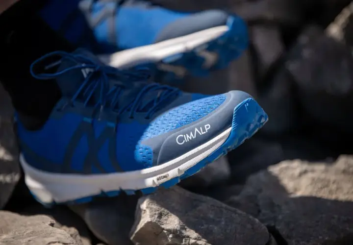 Chaussures de trail bleues CIMALP sur des rochers. Le bon **taille chaussure trail** est essentiel pour l'aventure.