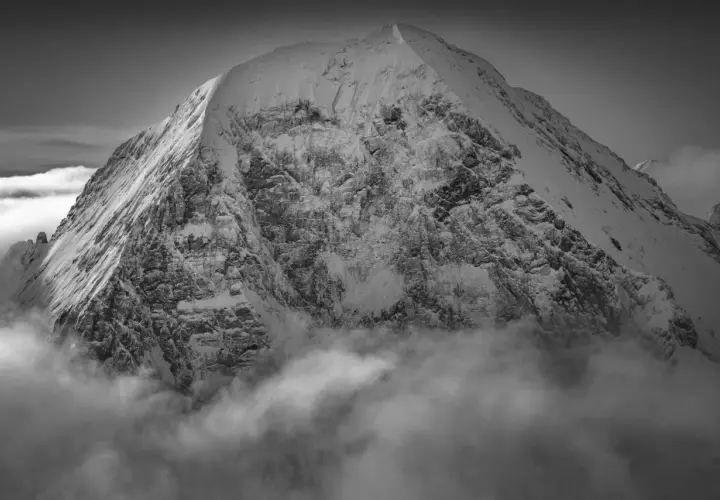 Sommet enneigé émergeant des nuages, une vision spectaculaire capturée par Guido Magnone.