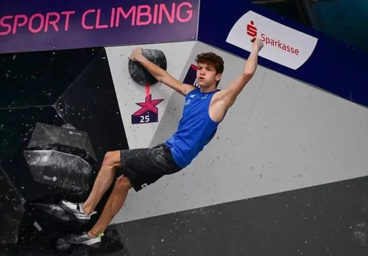 Mejdi Schalck, jeune grimpeur en action sur un mur de bloc, saisit une prise avec détermination.