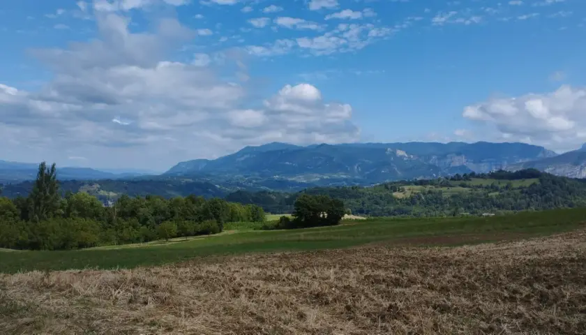 Paysage de montagnes bleues sous un ciel nuageux, parfait pour une randonnée près d'un pont en Royans.