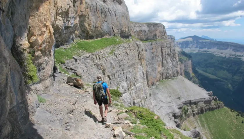 Randonneur sur le sentier escarpé de la Faja de las Flores, dominant un paysage de falaises et de vallées verdoyantes.