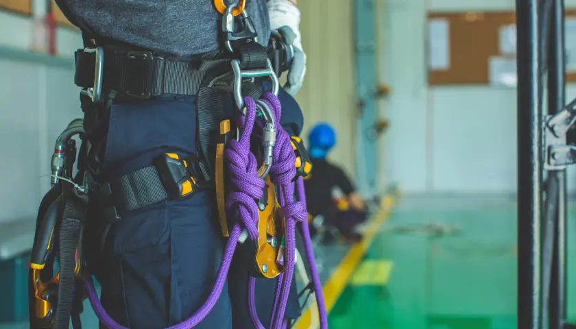 Un travailleur porte un harnais de sécurité avec une cordelette violette. Il est prêt pour une intervention en hauteur.