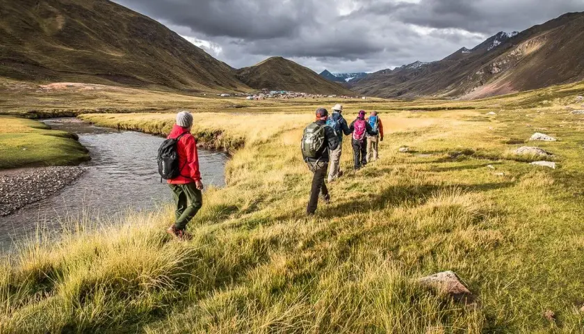 Un groupe de randonneurs s'engage dans un trek de 5 jours en France, traversant une vallée verdoyante avec une rivière sinueuse.