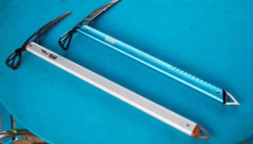 Deux piolets de montagne Petzl, un bleu et un argenté, prêts pour l'aventure.