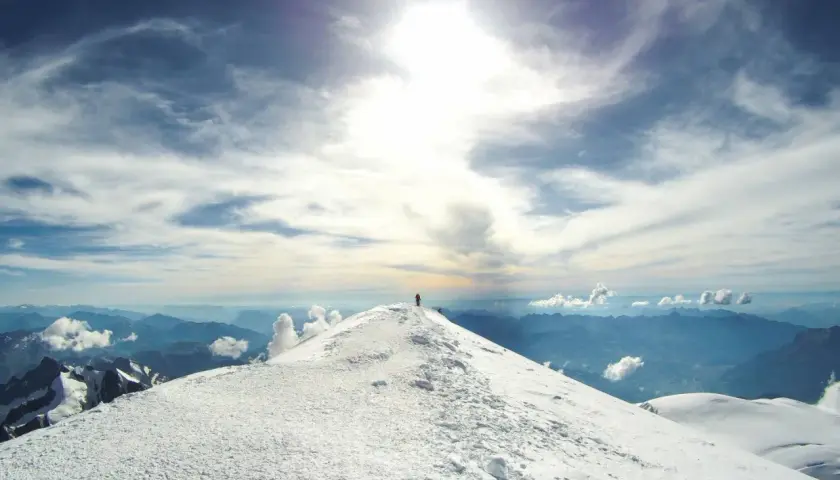 Un alpiniste solitaire au sommet du Mont Blanc, sous un ciel spectaculaire.