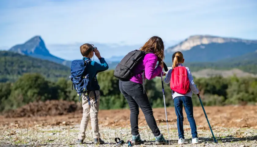 Une famille profite d'une randonnée à Font d'Urle. Le garçon utilise des jumelles, tandis que la mère et la fille consultent une carte.