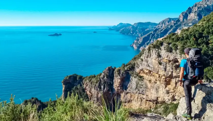 Randonnée sur la côte amalfitaine. Un randonneur admire la vue spectaculaire sur la mer bleue et les falaises escarpées.