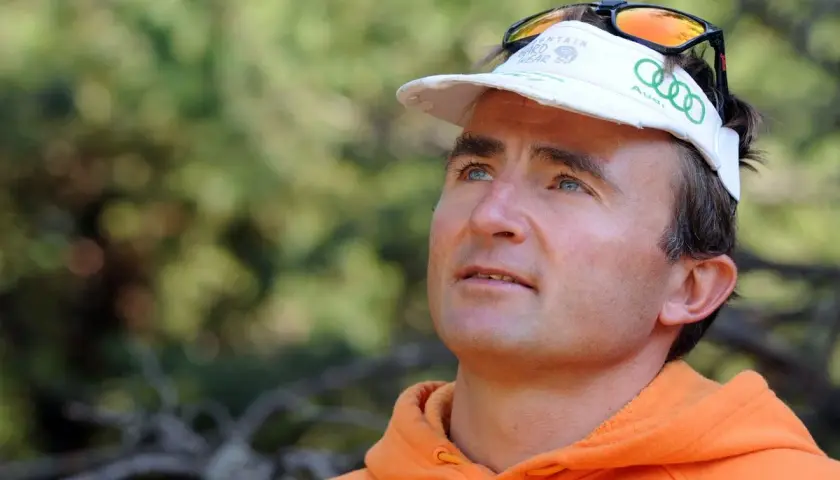 Portrait d'Ueli Steck, le célèbre alpiniste, avant son tragique accident. Il porte une casquette et un sweat orange.