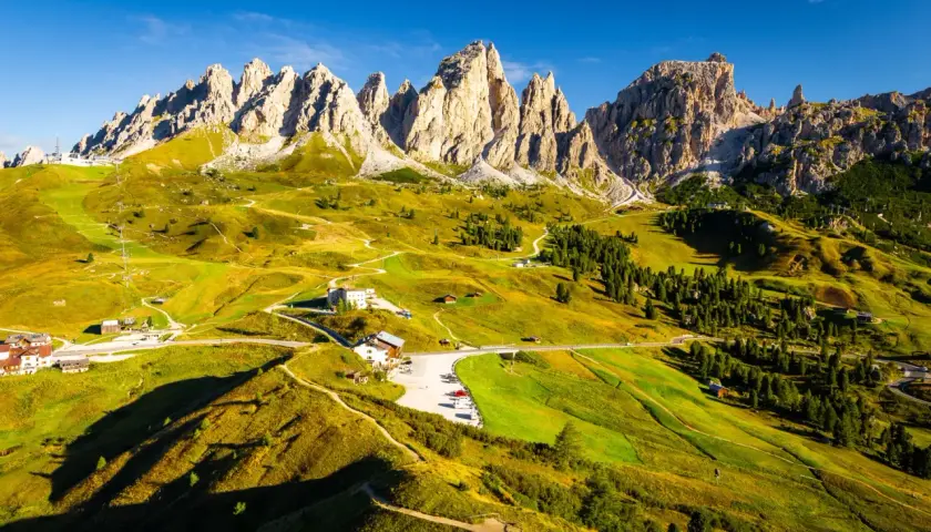 Paysage de montagne spectaculaire, avec des pics rocheux imposants et des prairies verdoyantes traversées par des sentiers. L'Alta Via 2 des Dolomites offre une vue imprenable.