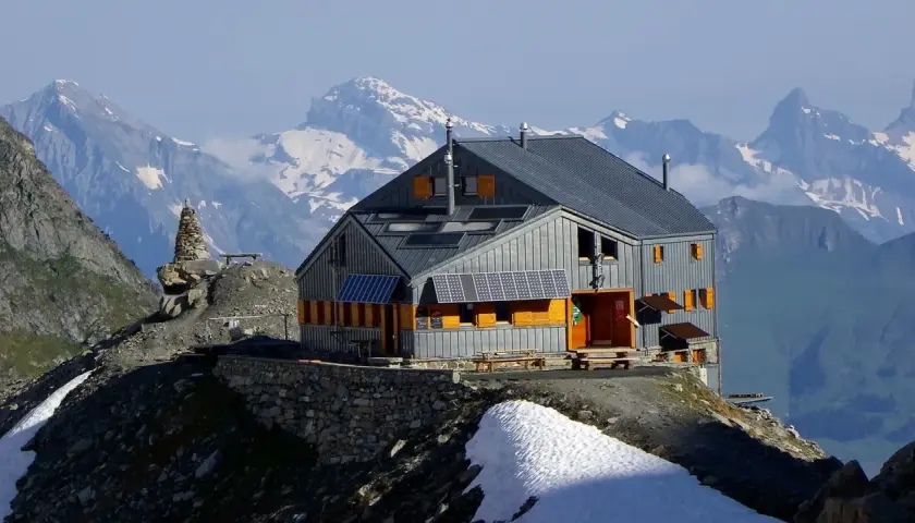 Refuge moderne sur fond de montagnes enneigées, un point de départ idéal pour le tour du Grand Combin. Panneaux solaires sur le toit.