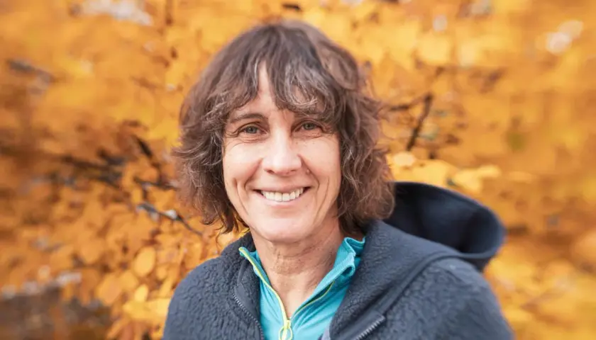 Catherine Destivelle, souriante, en tenue de sport, avec un fond d'automne. Elle est une alpiniste reconnue, un vrai compagnon de la nature.